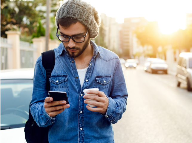 Man tittar på telefon och dricker kaffe